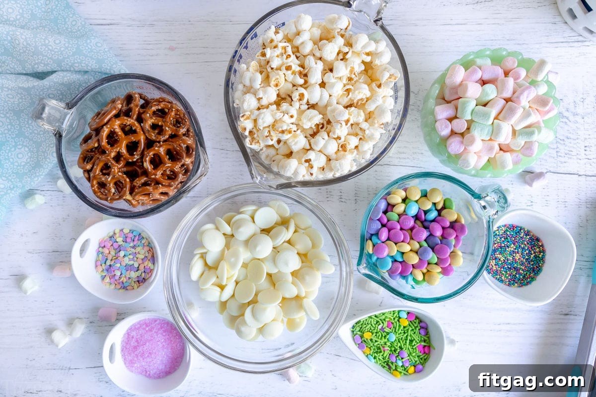 Hoppy Easter Snack Blend 5 Individual ingredients for Bunny Bait Easter Snack Mix, including popcorn, candy melts, pretzels, M&Ms, sprinkles, and marshmallows, neatly arranged in small bowls.