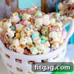 Easter snack mix in a white basket with pretzels, marshmallows and popcorn.