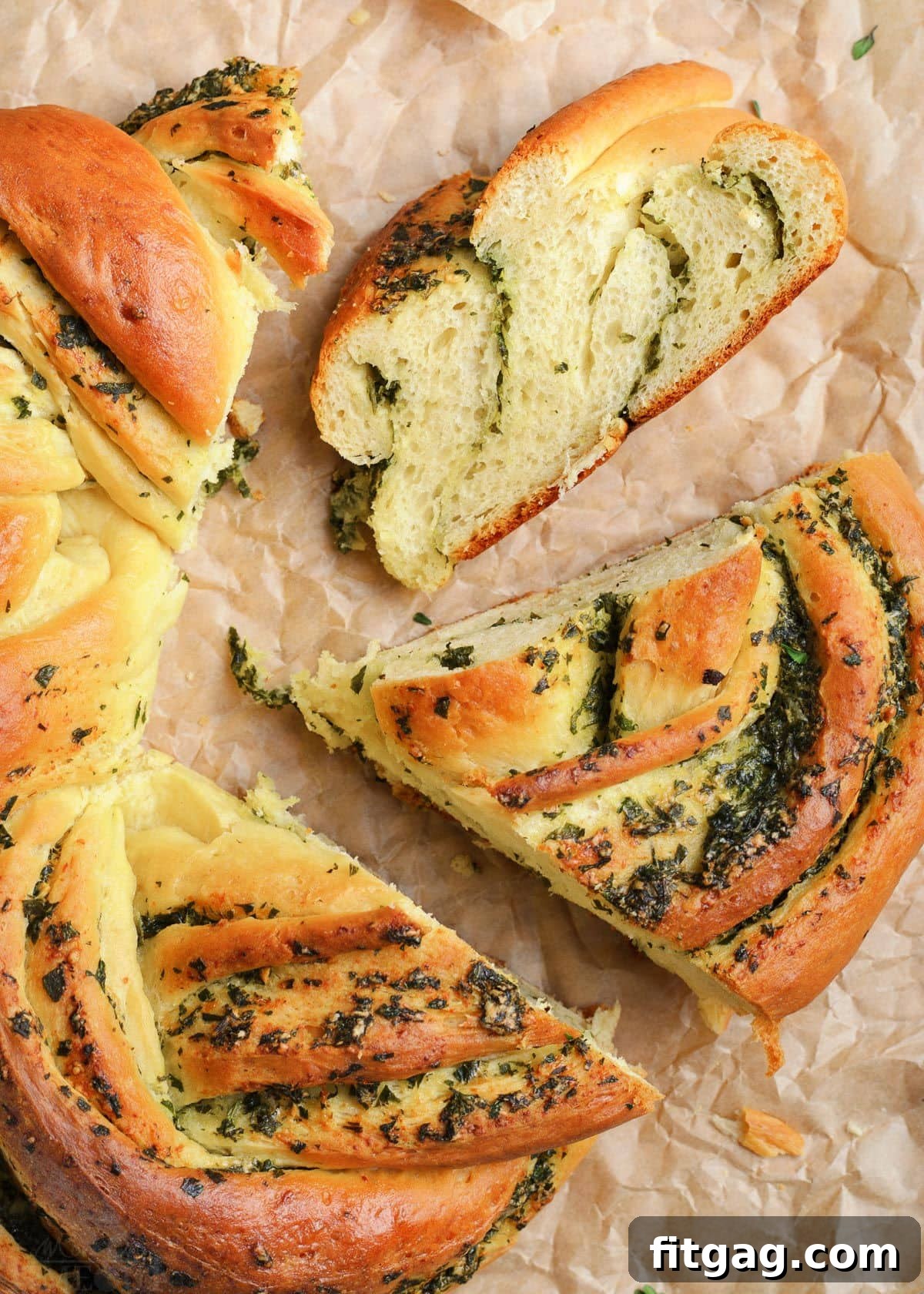 A top-down view of the golden-brown garlic herb bread wreath with several slices cut and ready to serve, highlighting its intricate twists and appealing texture.
