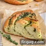 A close-up of a slice of Garlic Herb Bread Wreath on brown parchment paper, showing its beautiful texture and filling.