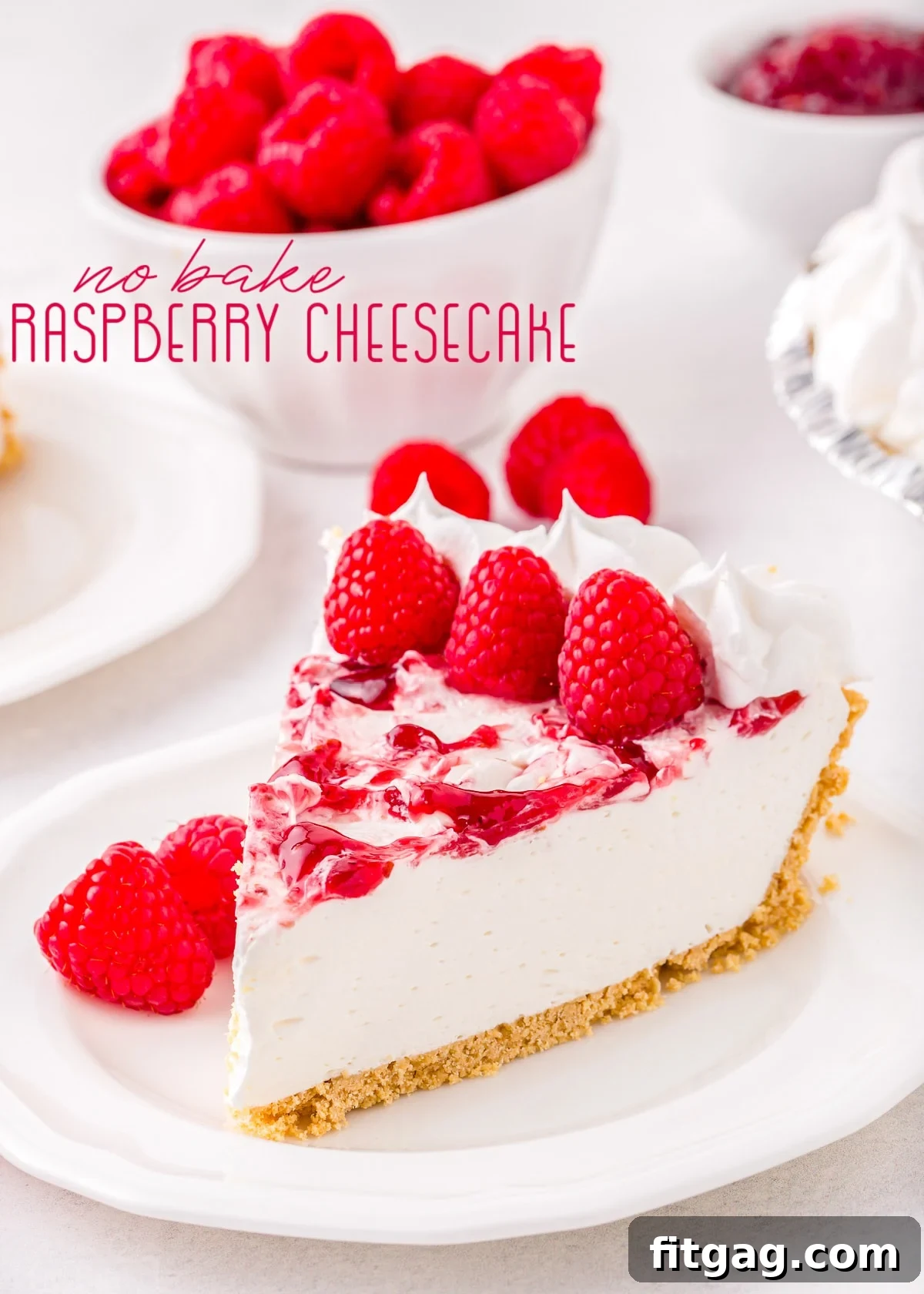 A beautifully presented slice of no-bake raspberry cheesecake on a plate, garnished with fresh raspberries and a vibrant swirl.