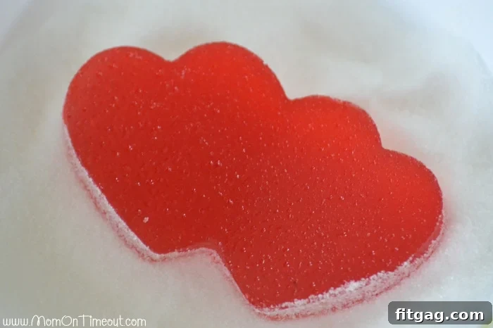 A child coating Valentine's Day Homemade Gumdrops in sugar, a delightful and interactive step in the candy-making process. #homemadecandy #valentinesdaytreats
