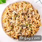 top down view of mushroom stroganoff piled high on round white plate garnished with parsley.