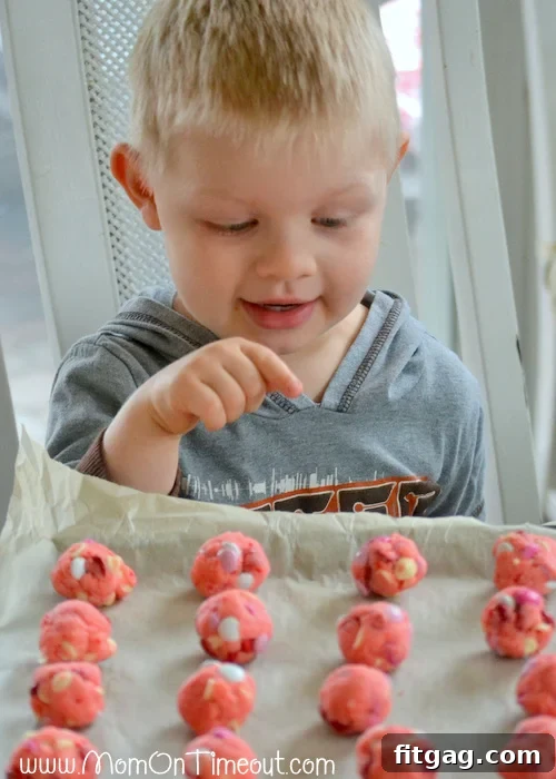 A charming image of a child's hand reaching for a strawberry cake mix cookie, showcasing the irresistible appeal of these delightful treats.