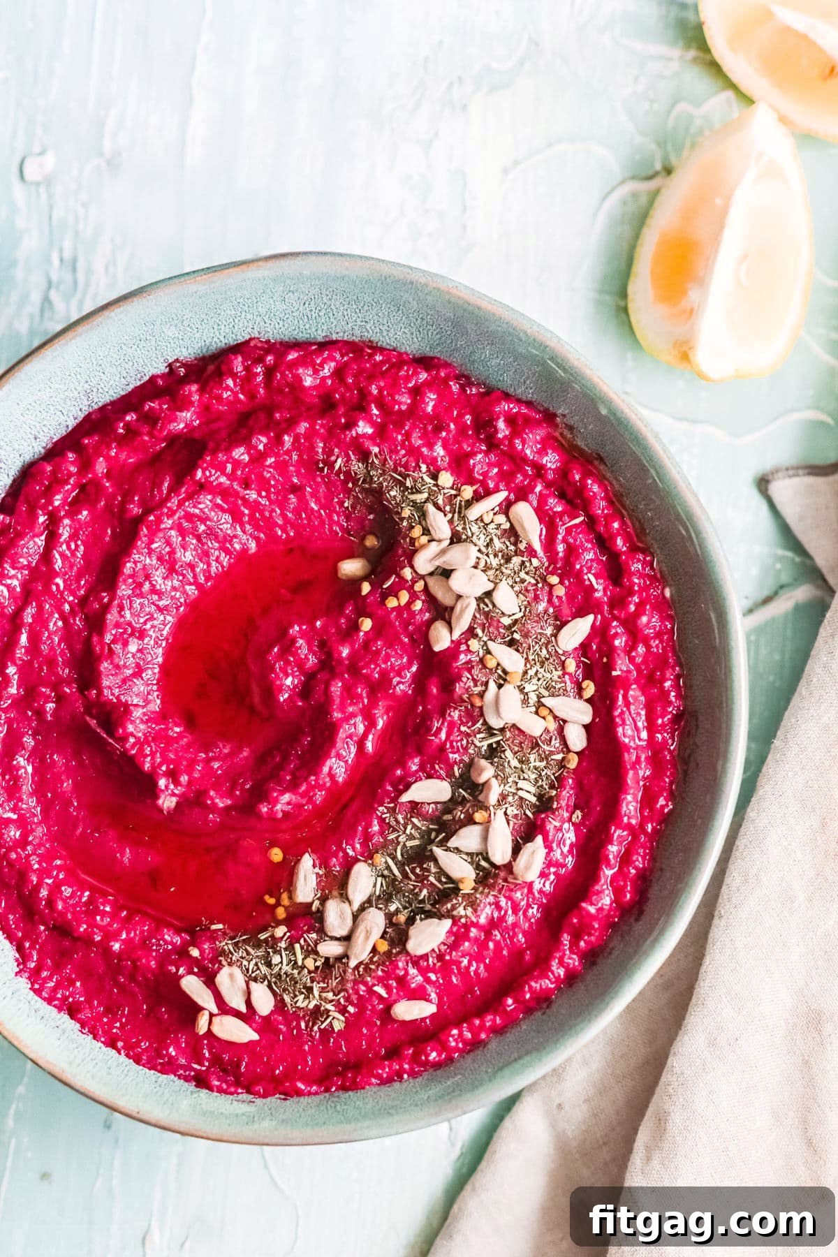 Vibrant Beet Hummus: Your Everyday Delight 3 Vibrant roasted beet hummus presented in a blue bowl, beautifully topped with a medley of sesame seeds and a drizzle of premium olive oil, ready to be served.