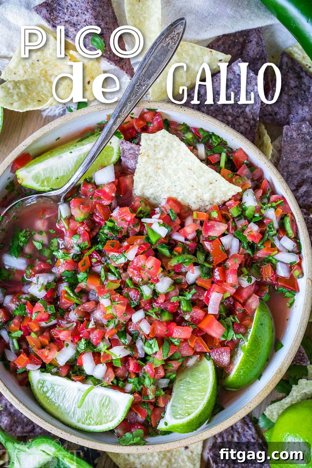 top down view of pico de gallo in clay bowl garnished with lime wedges and surrounded by chips. title overlay at top of image.