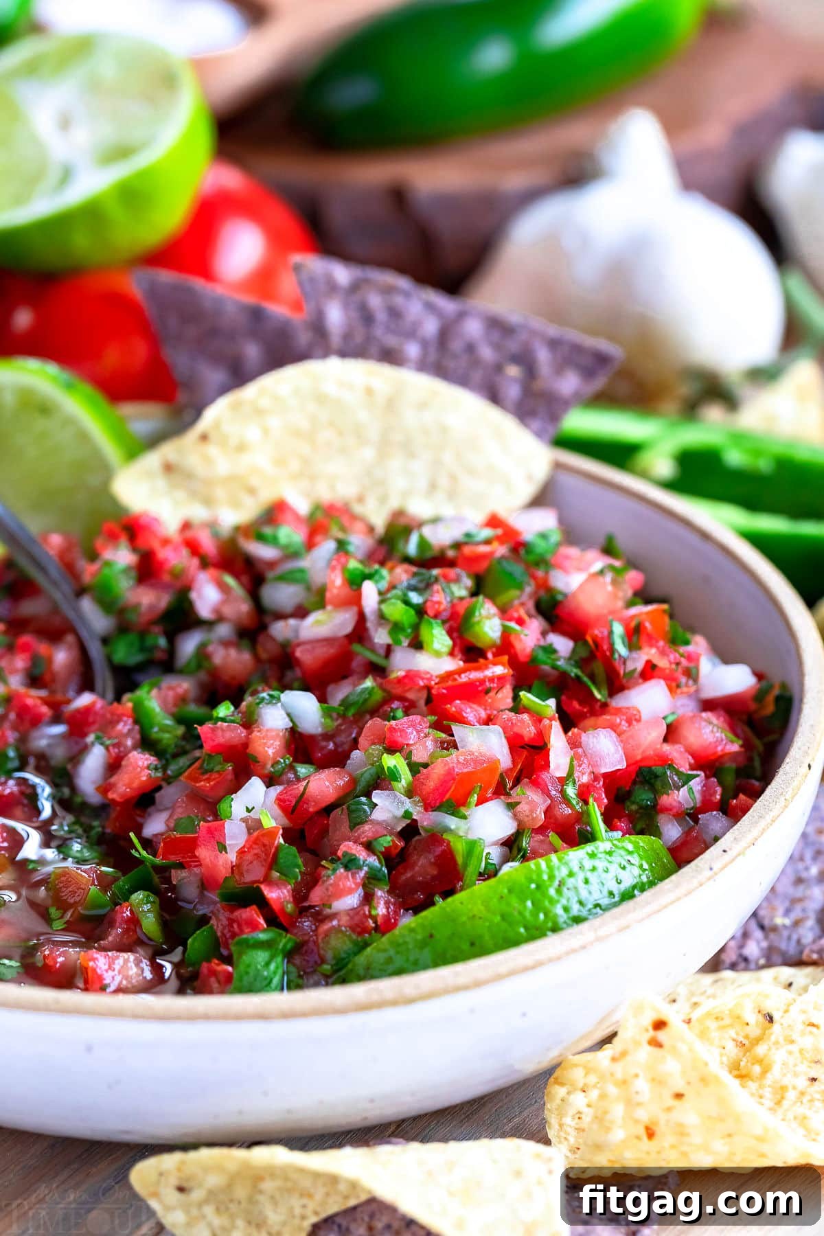 beautiful salsa in white bowl with lime wedges and tortilla chips. 