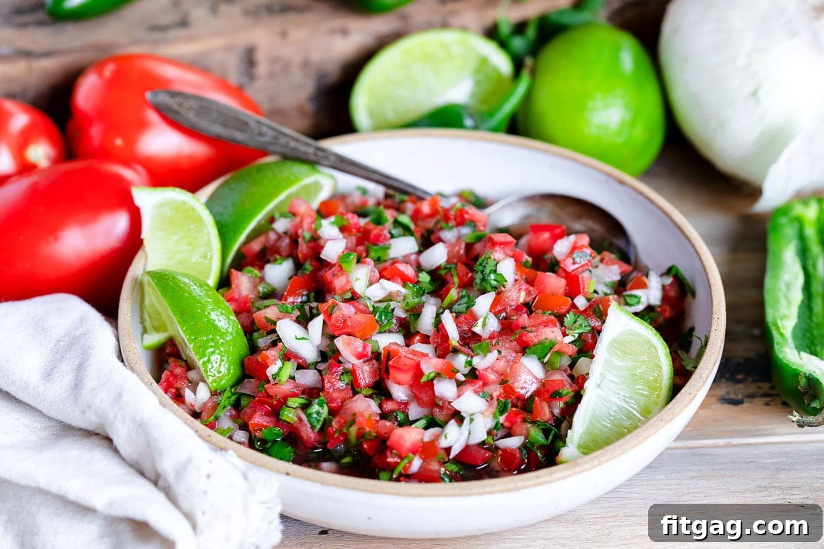 salsa fresco or pico de gallo in bowl ready to be enjoyed with ingredients behind it.
