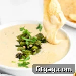 Irresistible Queso Blanco Dip 8 chip being dipped in queso blanco with charred poblanos on top.