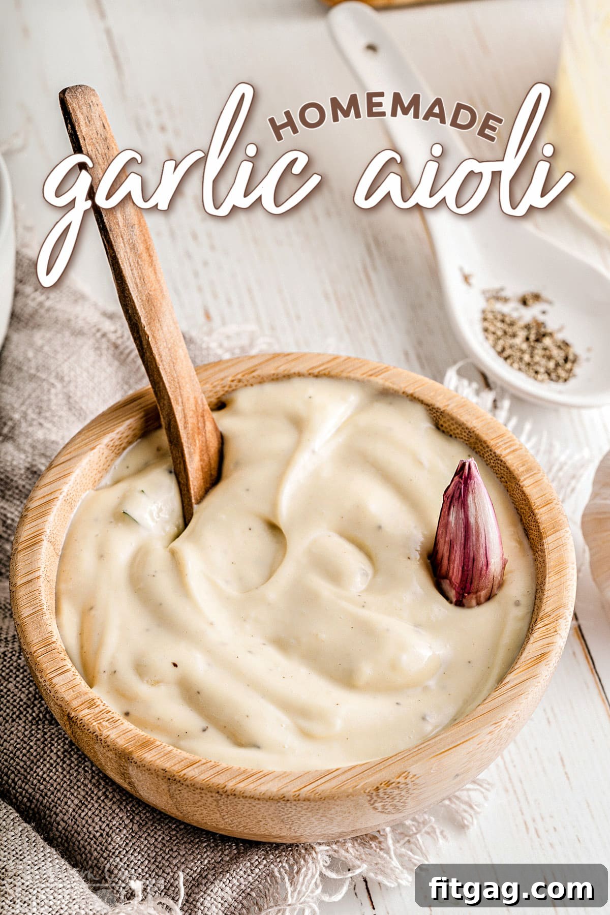 Homemade garlic aioli in a small wooden bowl, garnished with a fresh garlic clove.