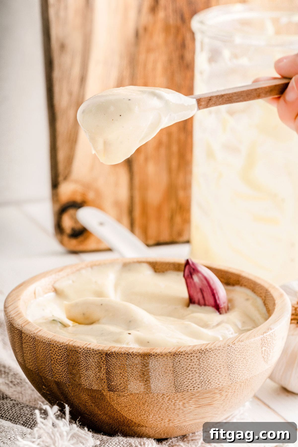 A spoonful of rich, creamy aioli held above a bowl brimming with the homemade sauce.