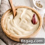 A small jar of garlic aioli with a spoon, highlighting its creamy texture.