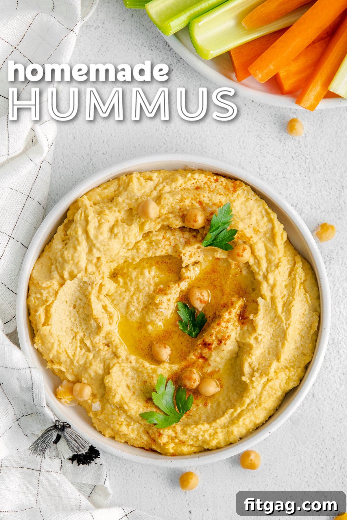 A shallow white bowl filled with creamy homemade hummus, garnished with a drizzle of olive oil and a sprinkle of paprika. Fresh carrots and celery sticks are neatly arranged on a plate next to it, inviting a delicious dip. Title overlay at top of image.