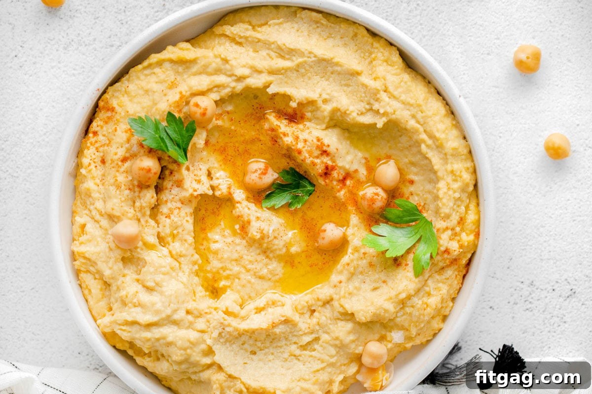 A bowl of finished homemade hummus, beautifully garnished with olive oil and paprika, ready to be served and enjoyed as a healthy and flavorful dip.