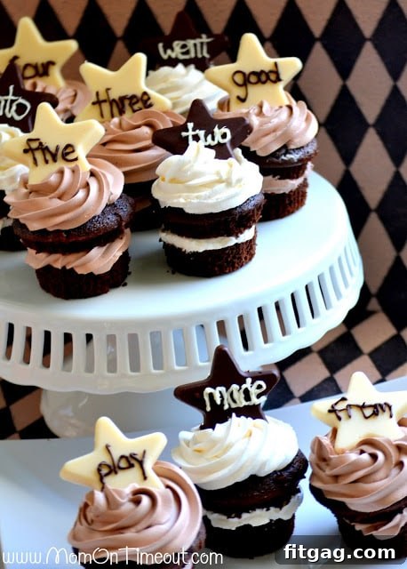 Close-up of Reece's hands holding an 'All Stars' chocolate cupcake, with a happy expression.