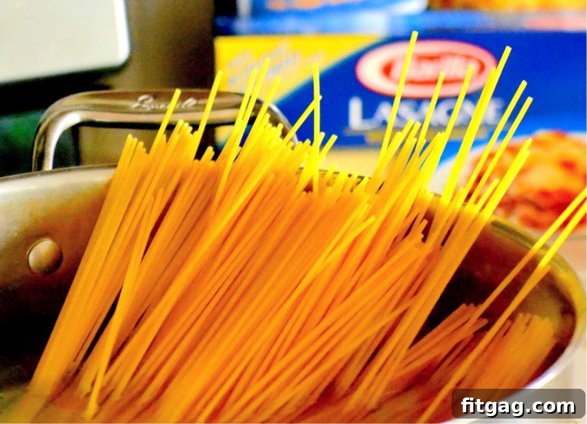 Spaghetti noodles submerged in a large pot of boiling water, midway through cooking.