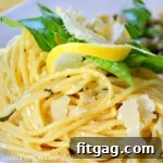 Plate of lemon spaghetti garnished with Parmesan, lemon, and basil.