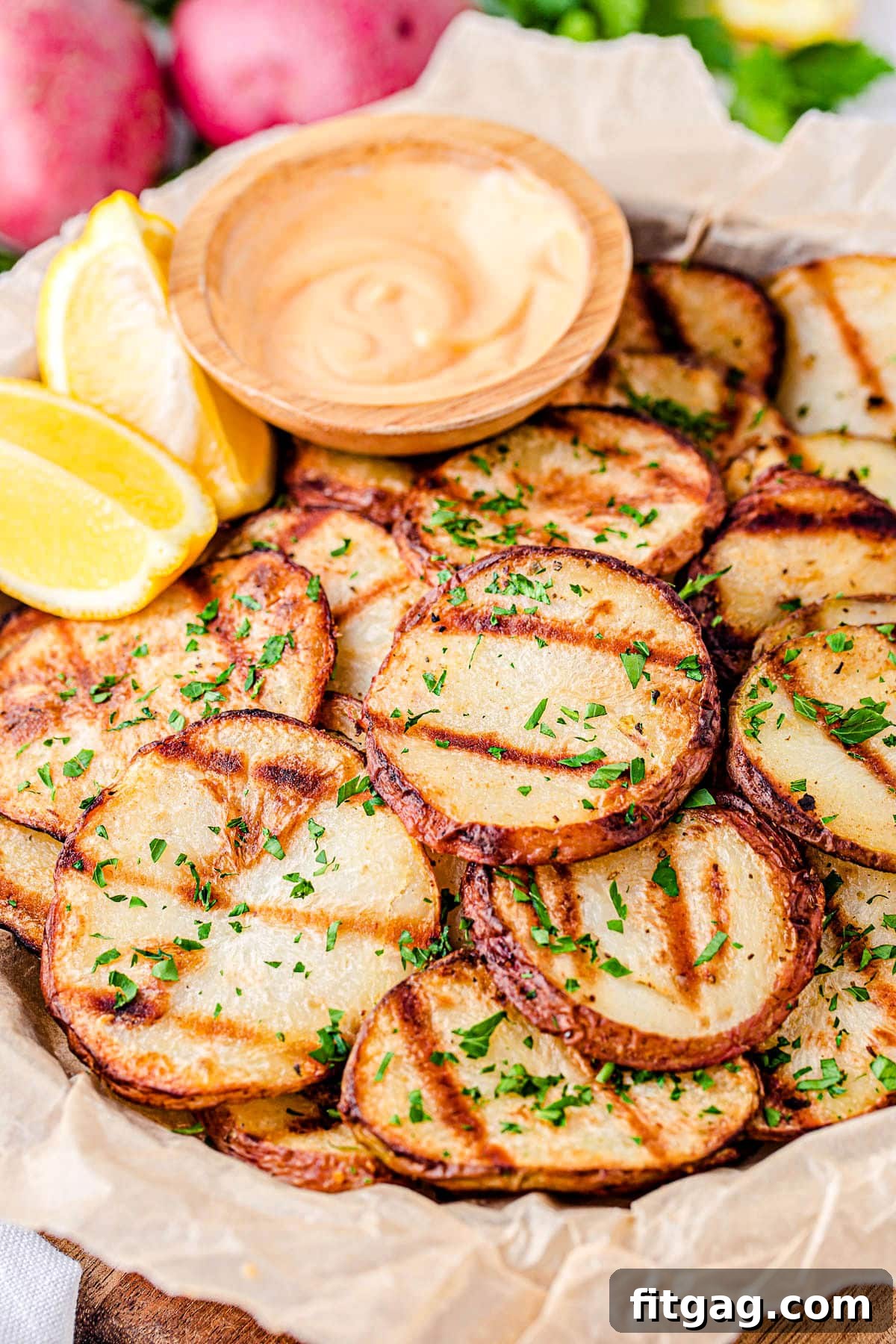 Smoky Garlic Herb Potatoes 2 Crispy grilled potatoes served with a spicy mayo dip and fresh lemon wedges on a rustic wooden tray, perfect for any outdoor gathering.
