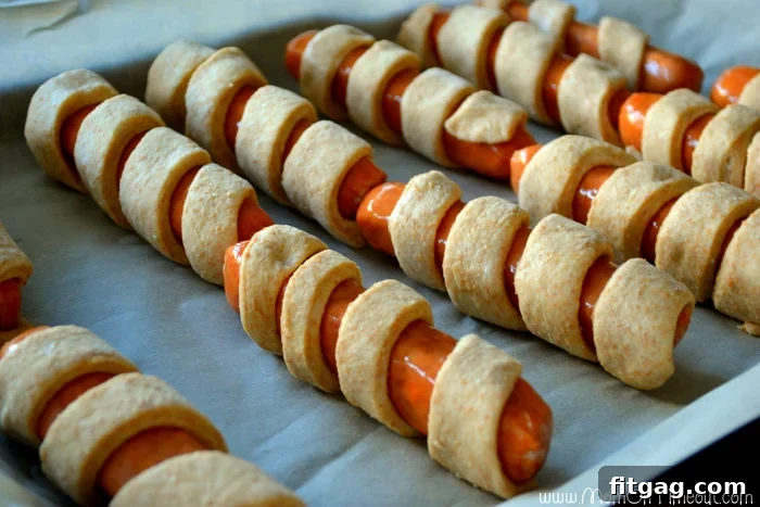 Rolling sausages in homemade yeast dough, a step-by-step image showing how to prepare Spiral-Wrapped Sausages on a Stick.
