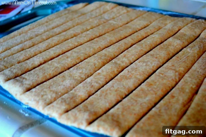 Close-up image of the yeast dough after being cut into strips with a pizza wheel, ready for wrapping around sausages. Demonstrates a key step in making spiral sausages.