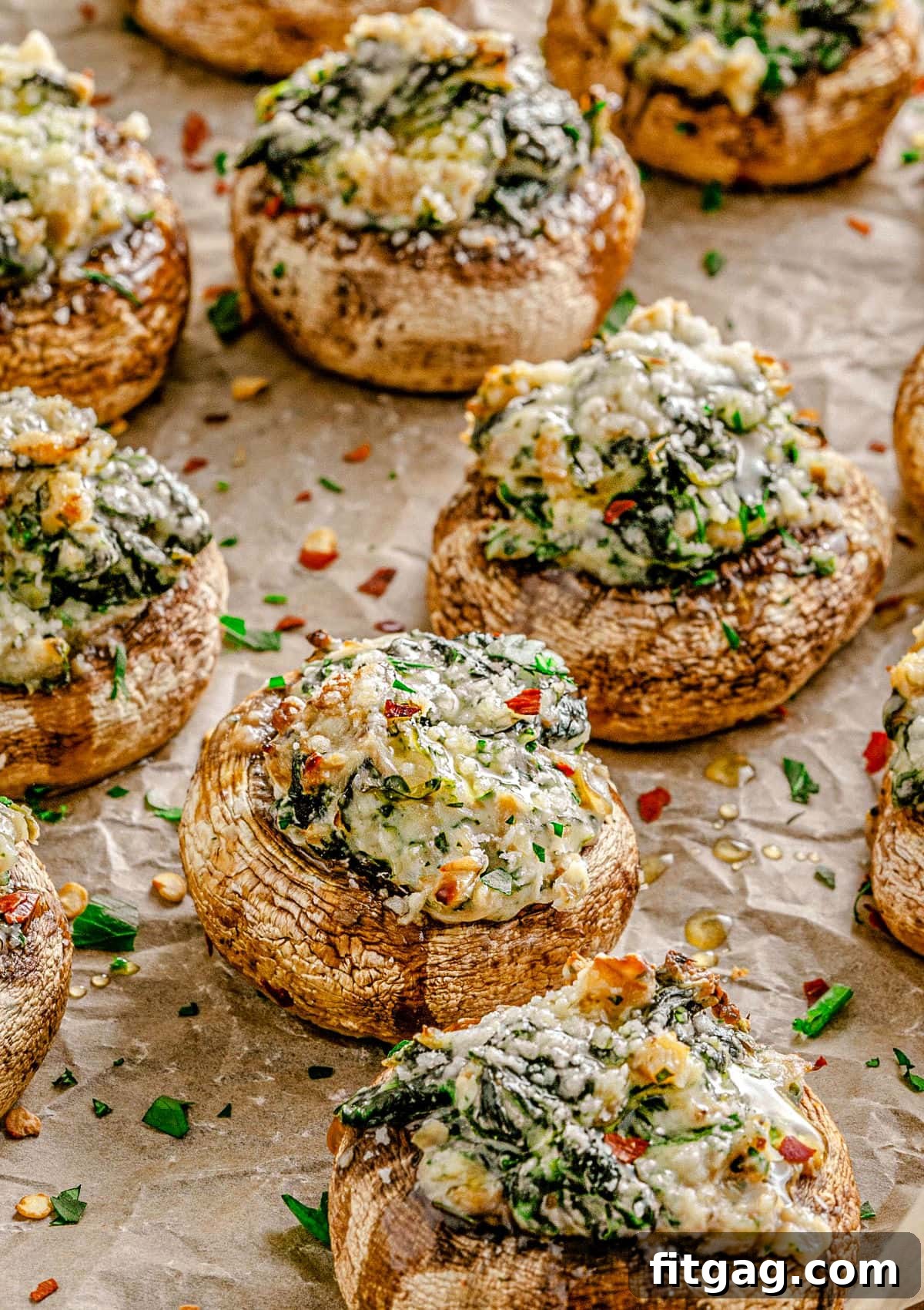 Irresistible Stuffed Mushrooms 2 Freshly baked spinach and cream cheese stuffed mushrooms on brown parchment paper, ready to be served.