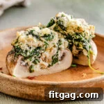 Irresistible Stuffed Mushrooms 8 A perfectly halved stuffed mushroom on a brown plate, showcasing its creamy spinach and cheese filling.