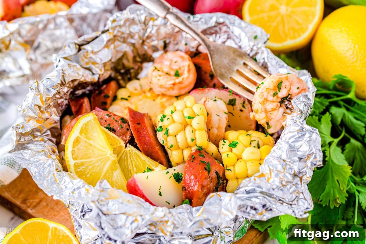 Effortless Shrimp Foil Packs 3 shrimp boil foil packs opened up and a shrimp on a fork ready to eat.