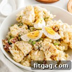 Cauliflower salad made like potato salad in a white bowl, garnished and ready to serve at a gathering.