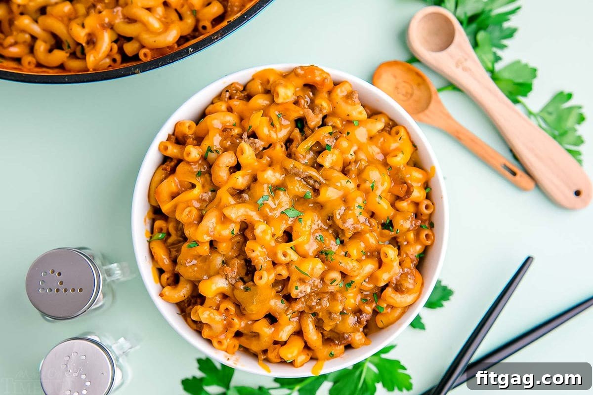 homemade hamburger helper served in a small white bowl on a mint green background.