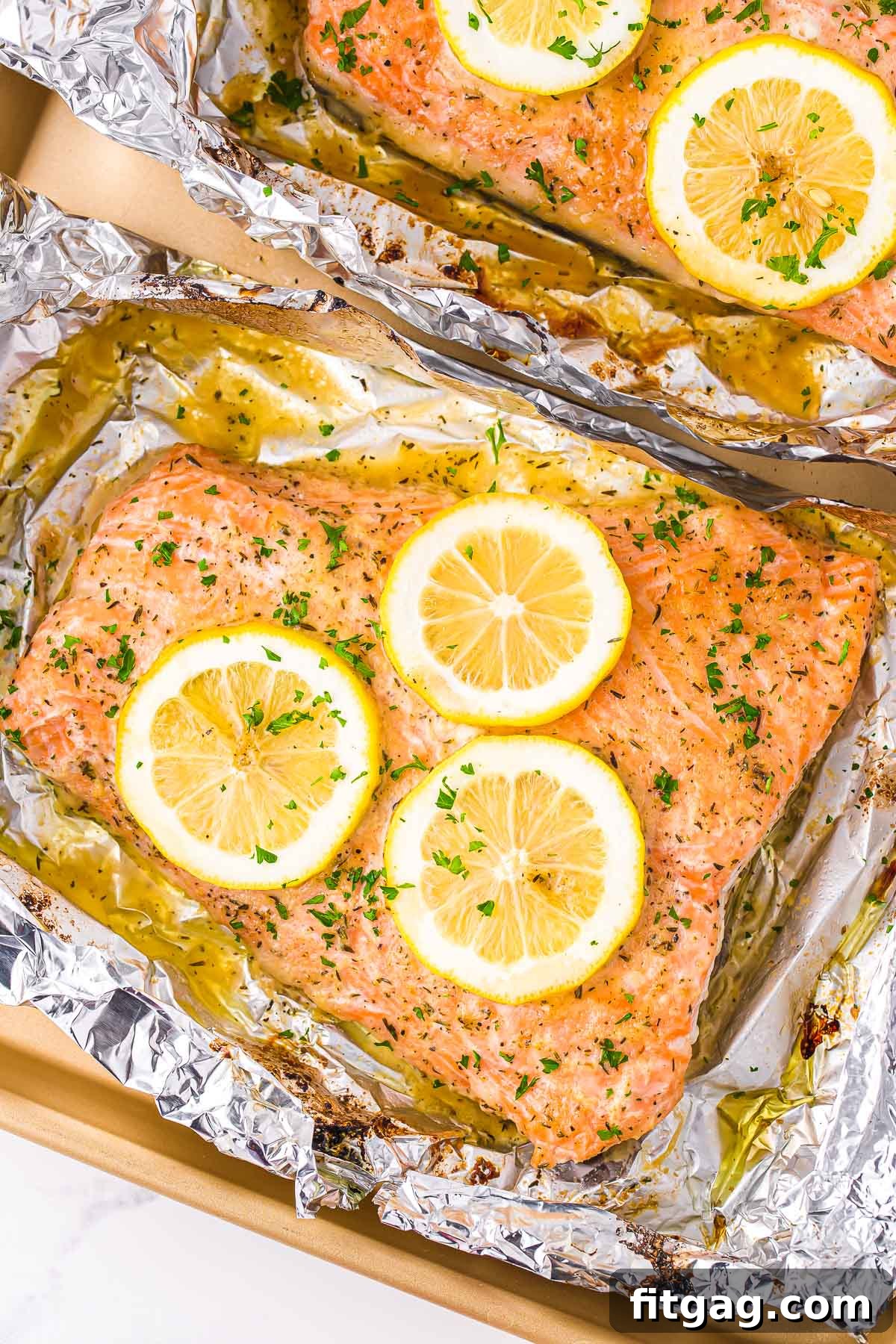 Perfectly baked salmon in foil, garnished with vibrant lemon slices and fresh parsley, ready to be served.