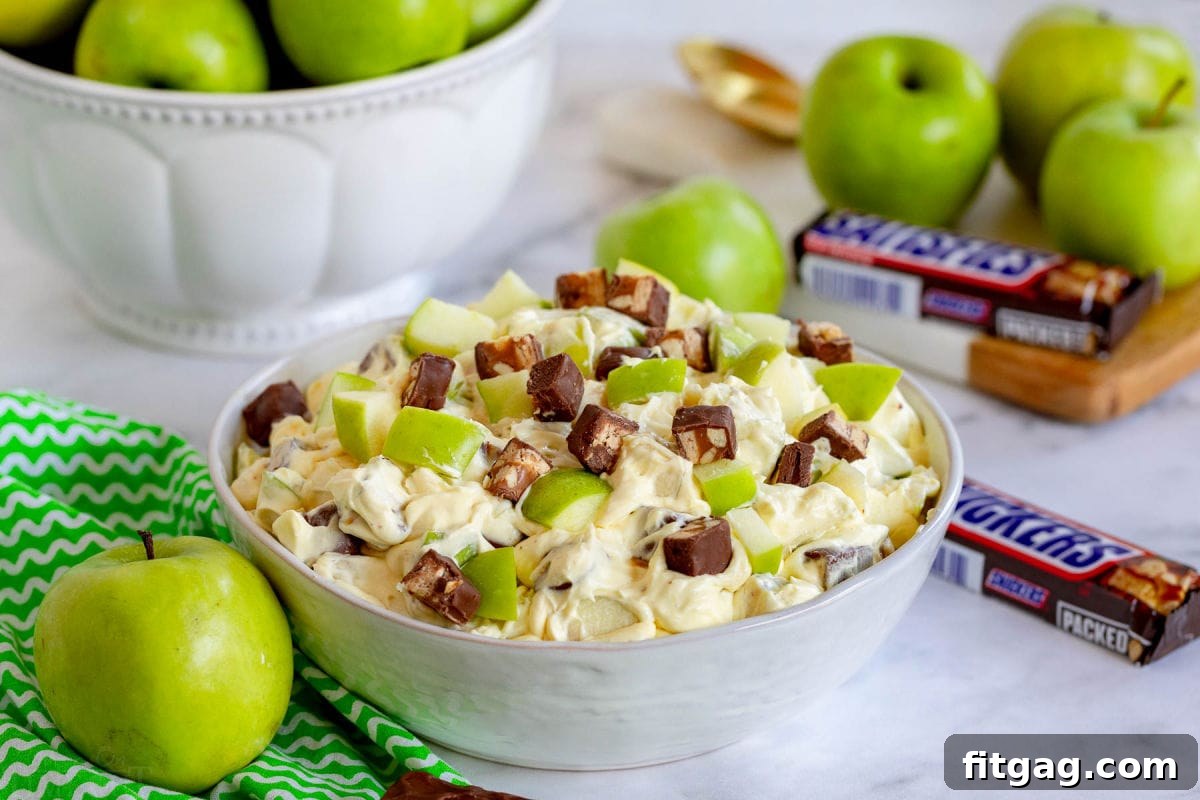 Snickers Caramel Apple Delight 3 apple salad with snickers mixed in in large white bowl.