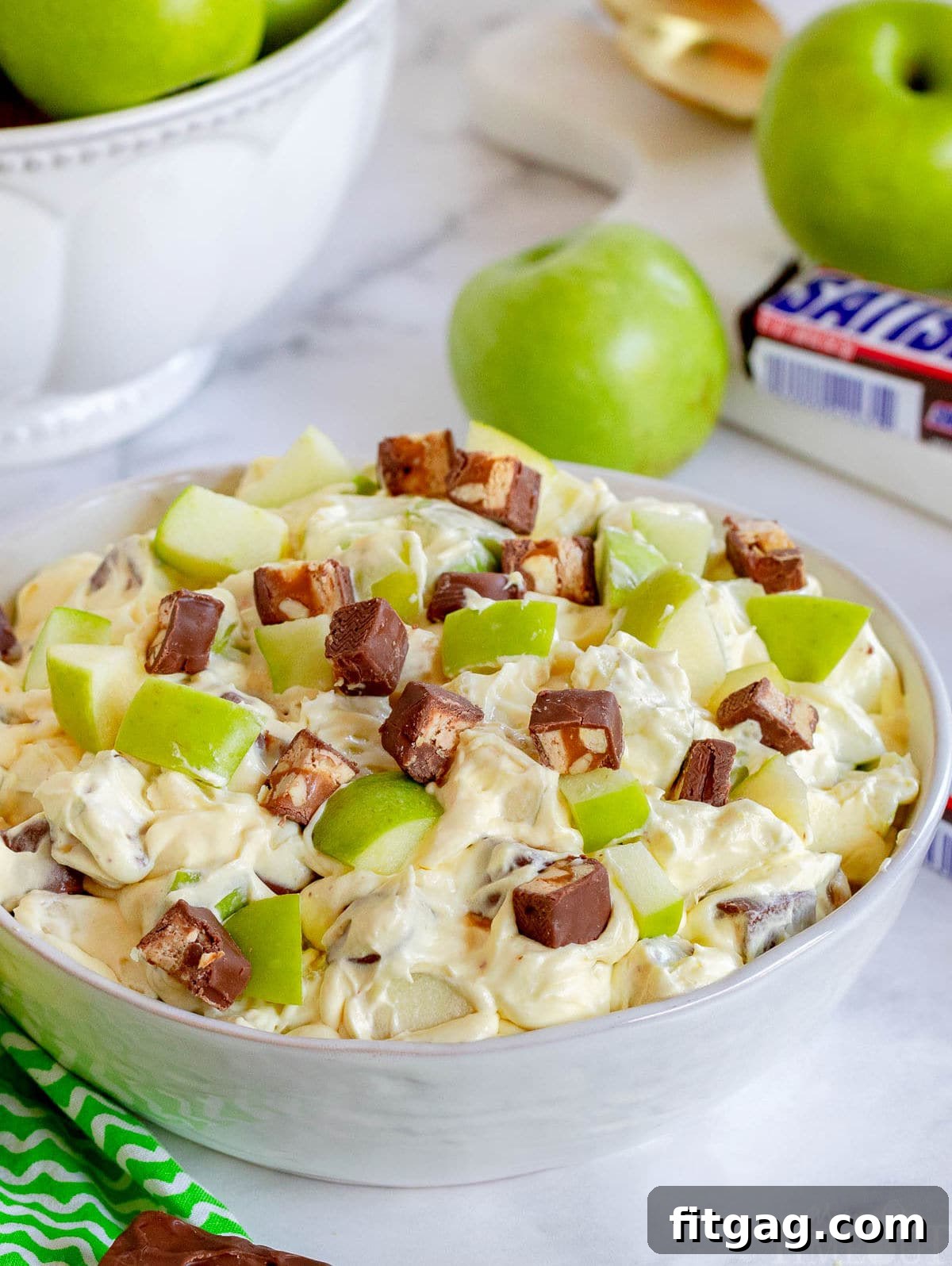 Snickers Caramel Apple Delight 8 apple salad with snickers mixed in in large white bowl.
