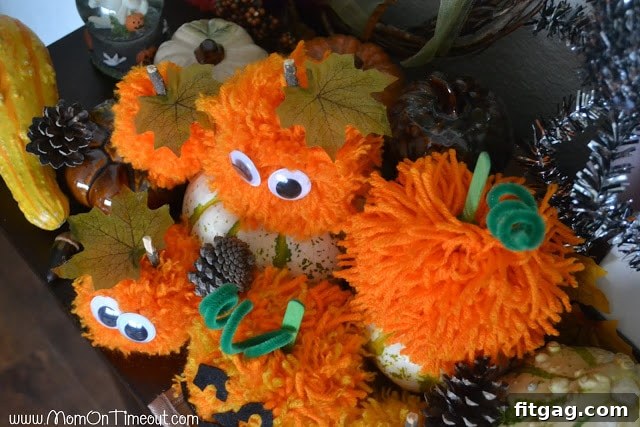 An aerial view of multiple finished pom pom pumpkins, highlighting their varied sizes, colors, and embellishments from above.