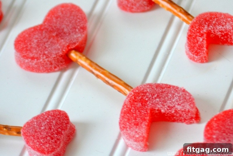 DIY Cupid's Arrows: Fun and Easy Valentine's Day Treat with Gumdrops and Pretzels Step-by-step assembly of a Cupid's Arrow, showing how to connect gumdrop hearts with a pretzel stick to form the edible craft.
