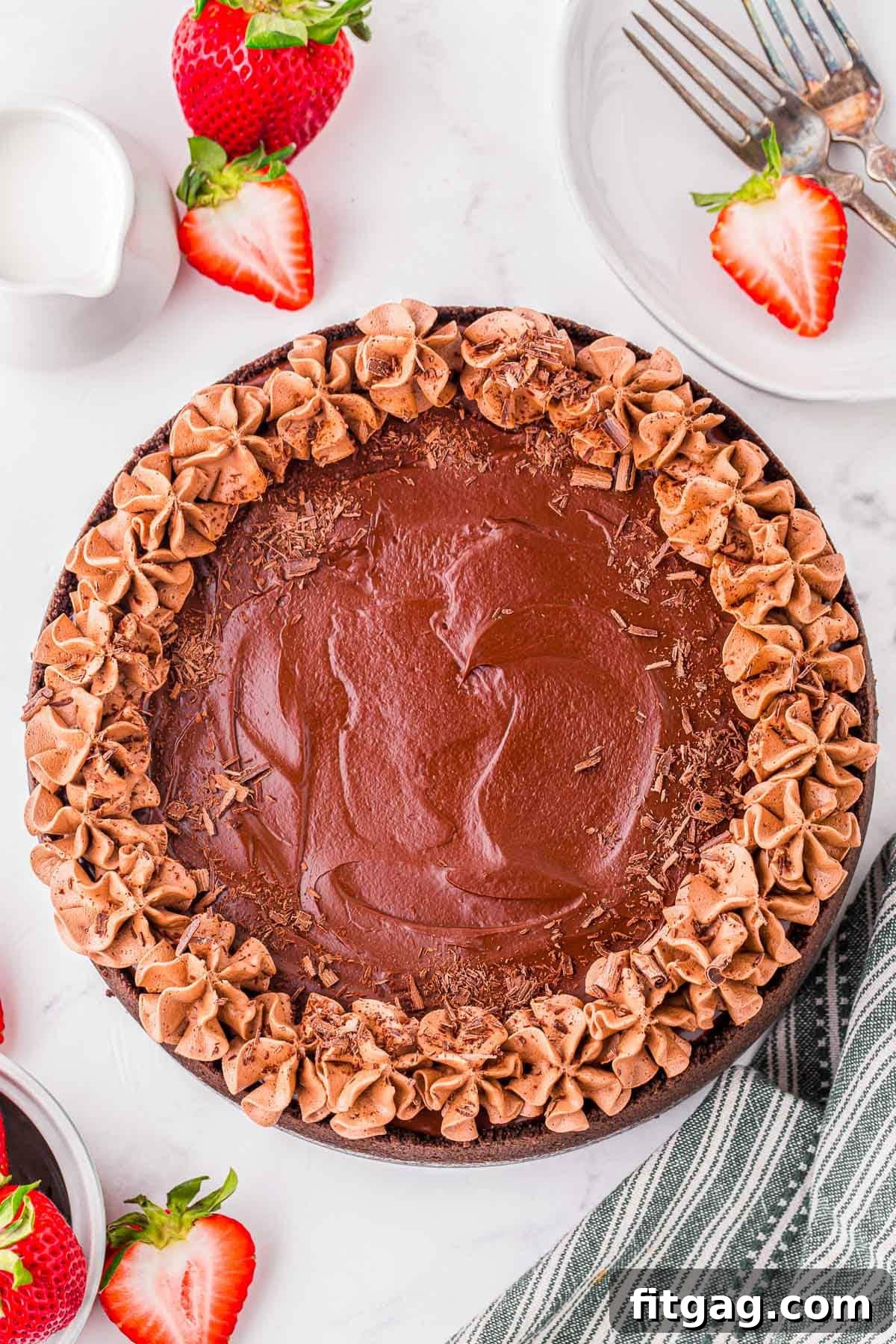 Top down look at whole chocolate cheesecake topped with chocolate shavings and whipped chocolate ganache.
