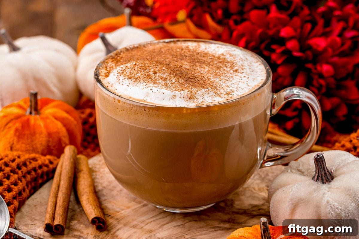 angled view of pumpkin spice latte so you can see the layers in the glass mug as well as the pumpkin pie spice topping.