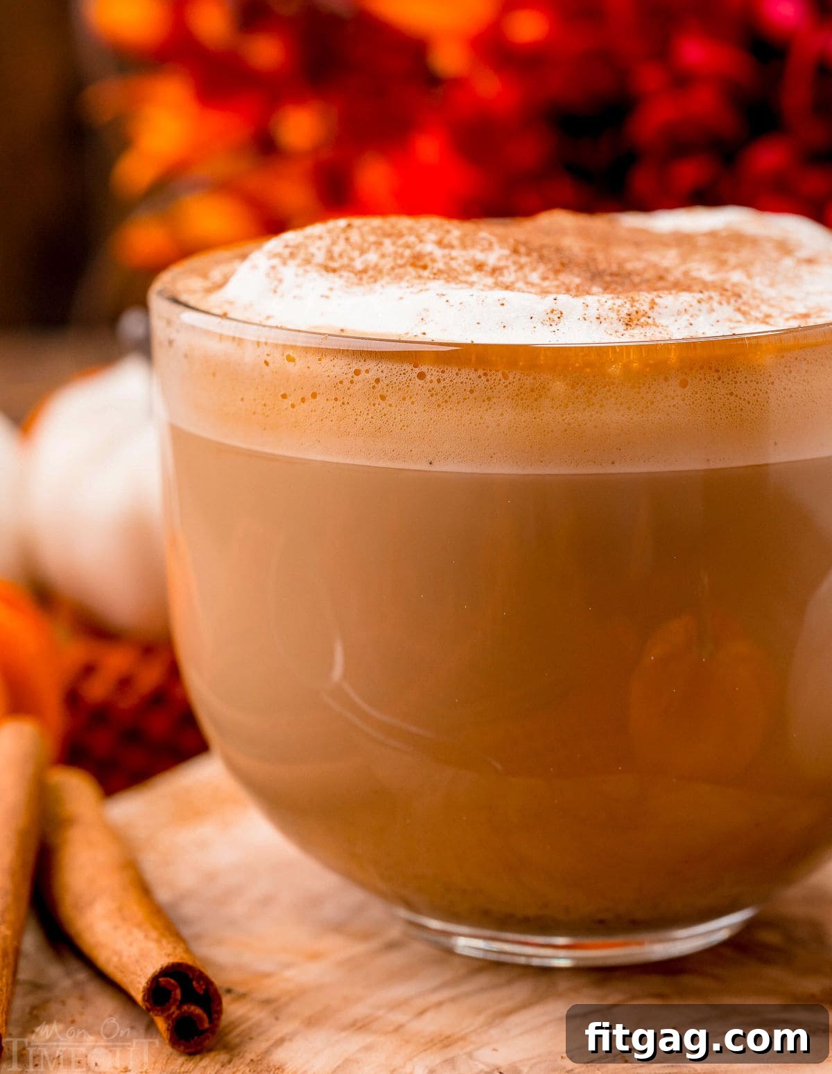 up close look at pumpkin spice latte made at home. Served in a glass mug and topped with frothed milk and pumpkin pie spice.