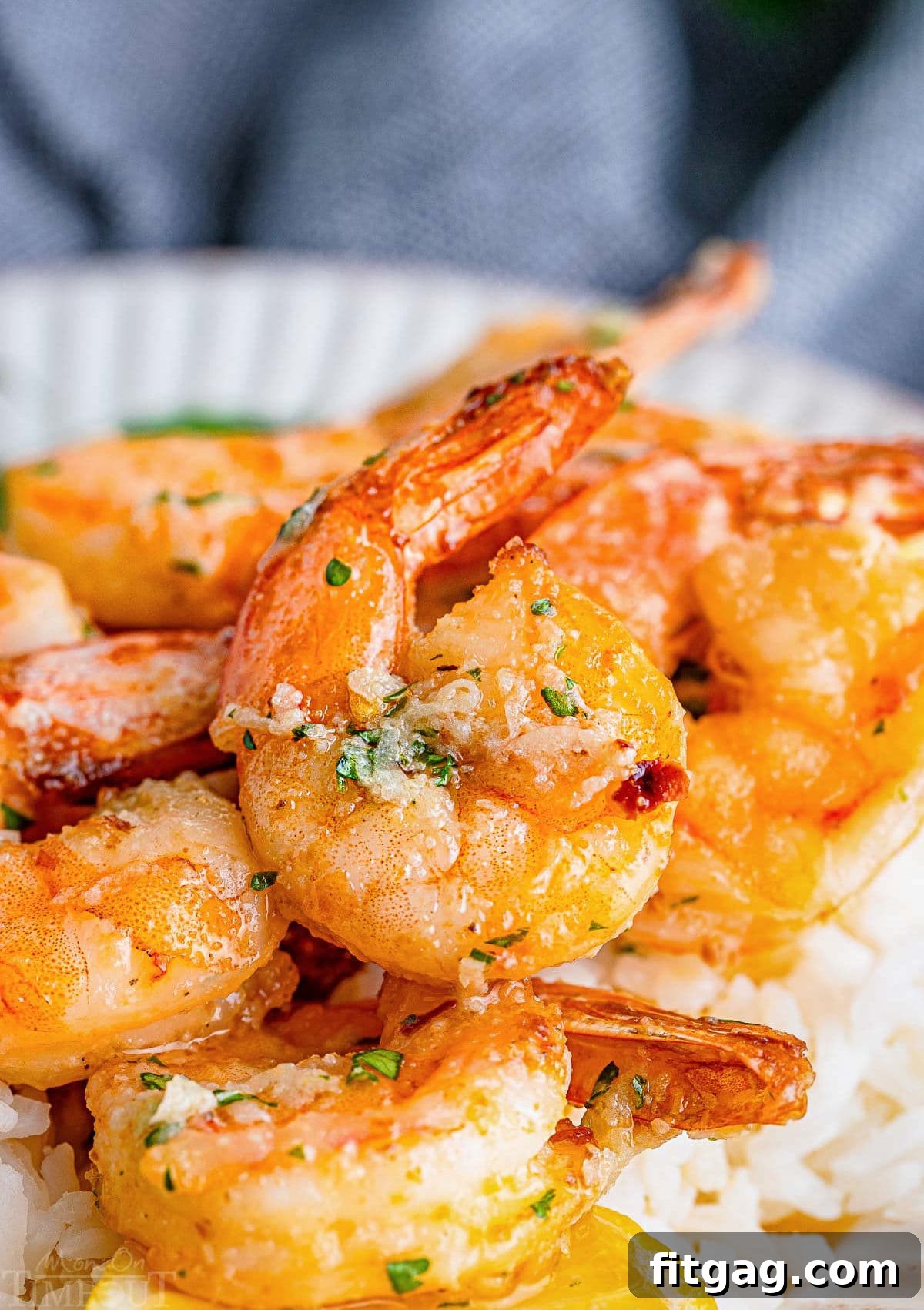 Effortless Air Fryer Shrimp 7 Close-up view of large, succulent air fryer shrimp topped with a rich garlic butter sauce, served elegantly on a bed of fluffy white rice.