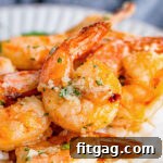 A close-up image of cooked air fryer shrimp with garlic butter on a plate.