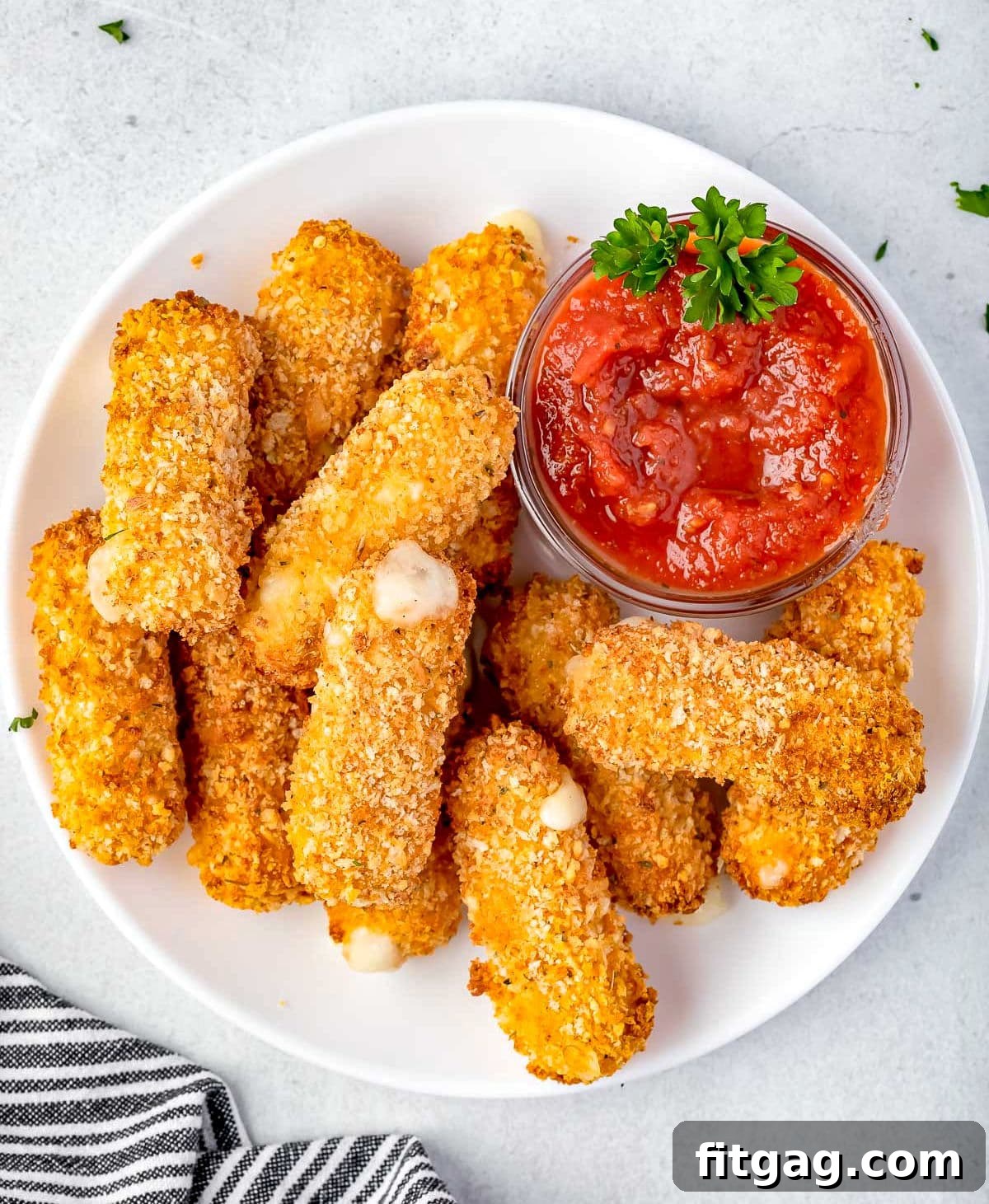 Golden Gooey Air Fryer Mozzarella Sticks 4 A top-down view of several perfectly cooked, golden-brown mozzarella sticks, ready to be enjoyed, on a white plate. Some are already bitten into, showing the melted cheese.