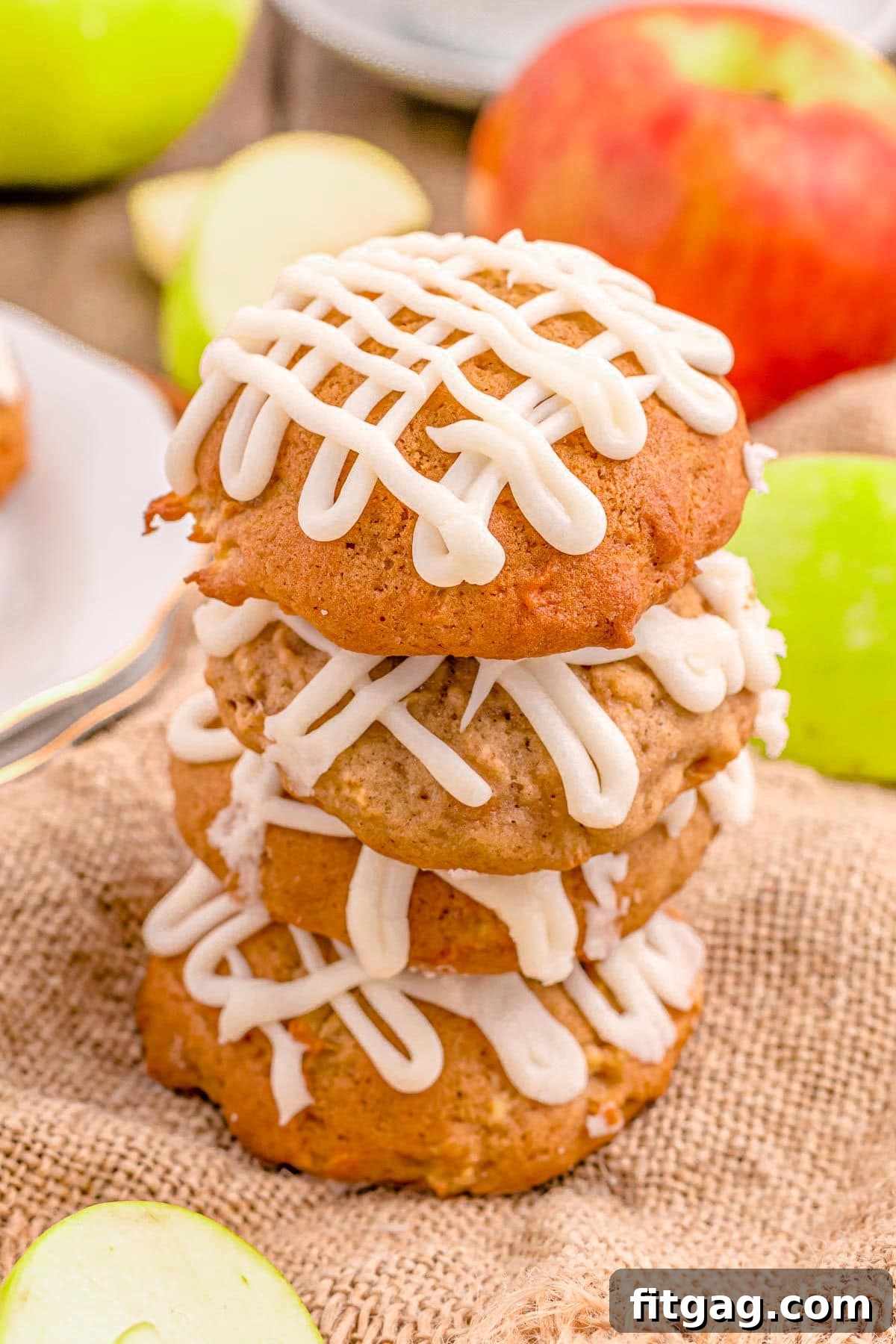 Three apple cookies are neatly stacked on top of each other, resting on a rustic piece of burlap, highlighting their appealing texture and rustic charm.