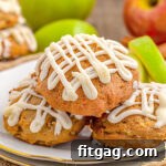 apple cookies sitting on white plate with gold rim with maple icing drizzle don top. fresh apples and apple slices in background.