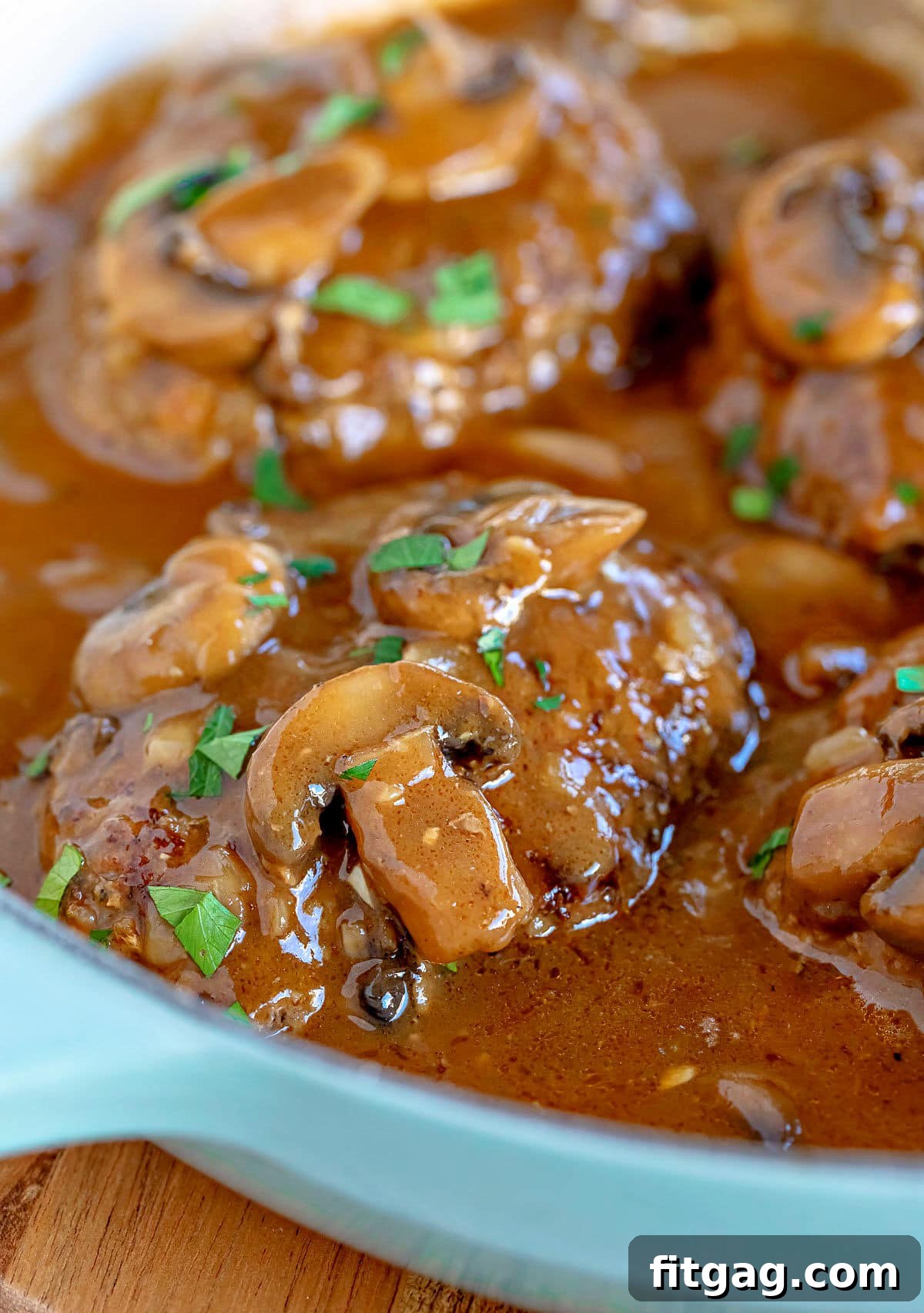 Easy Homestyle Salisbury Steak 2 Four golden-brown Salisbury steaks simmering in a rich mushroom gravy in a large skillet, garnished with fresh parsley.