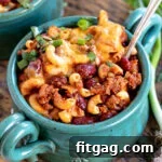 A small image of a teal bowl filled with chili mac and topped with shredded cheese and sliced green onions.