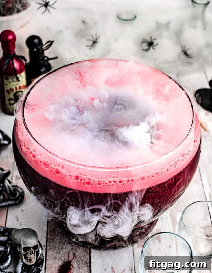 Dark red Halloween punch served in a large glass punch bowl, creating a mystical fog effect with dry ice.