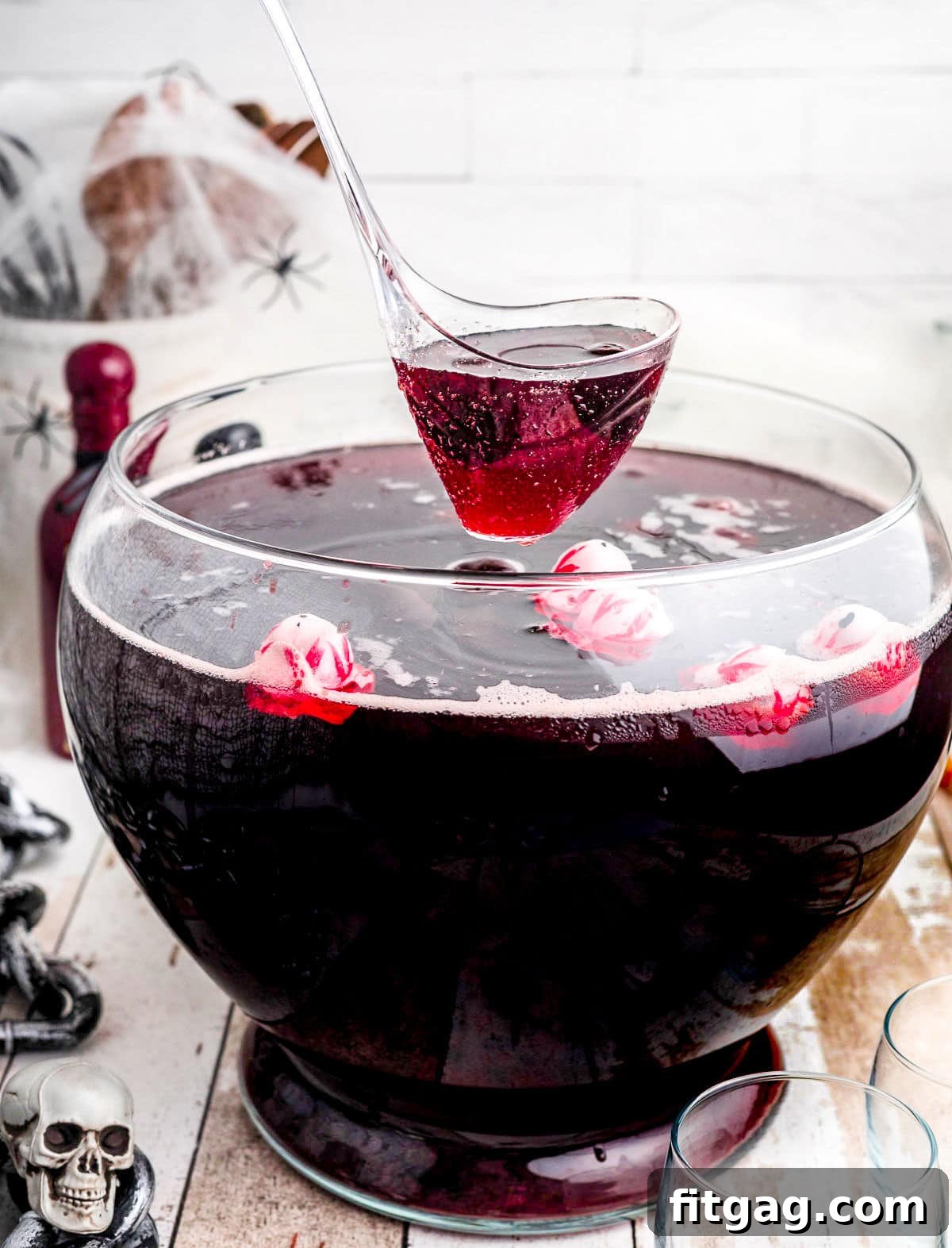 Punch being carefully ladled out of a large glass punch bowl, ready to be served.