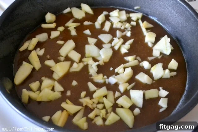 Diced apples sprinkled over a layer of caramel sauce in a baking pan, adding an extra fruity layer.