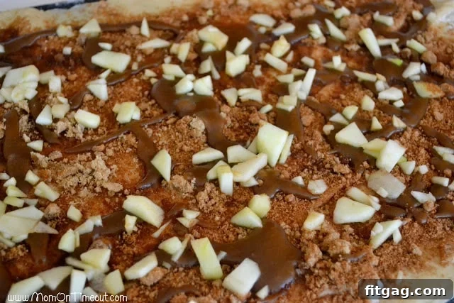 Diced apples scattered over the caramel, brown sugar, and cinnamon layers on the sticky bun dough.