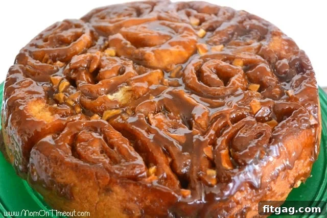 A close-up of a single Caramel Apple Sticky Bun, golden and covered in glossy caramel, ready to eat.