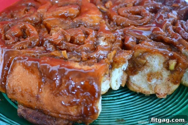 A plate holding a fresh Caramel Apple Sticky Bun, showing the gooey caramel and tender dough.